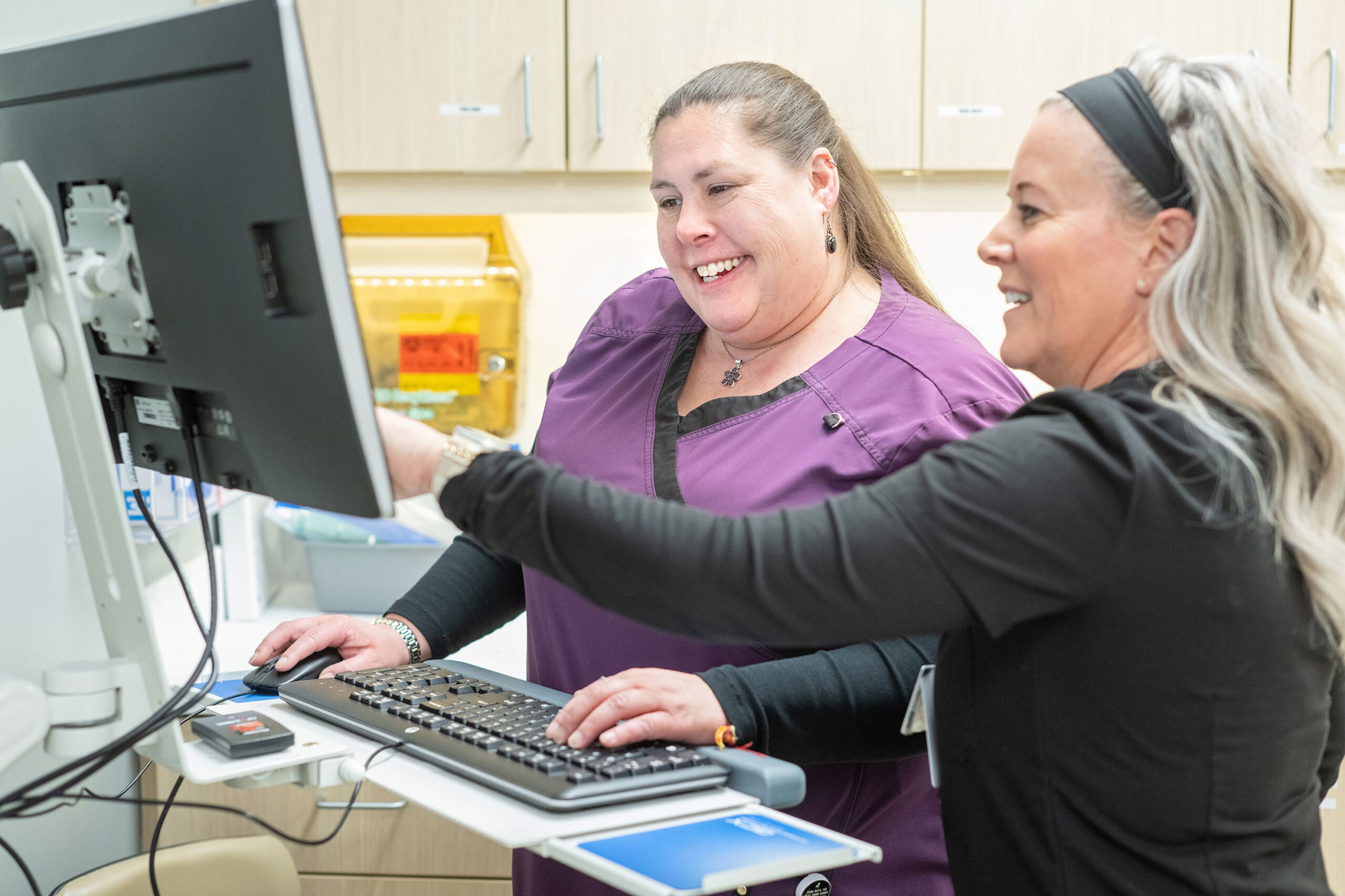 Registered Nurse Kathryn Perry and Medical Assistant Cassandra Graham-Petersen using a computer to view member information in the Centre Point medical center in Aurora, CO.