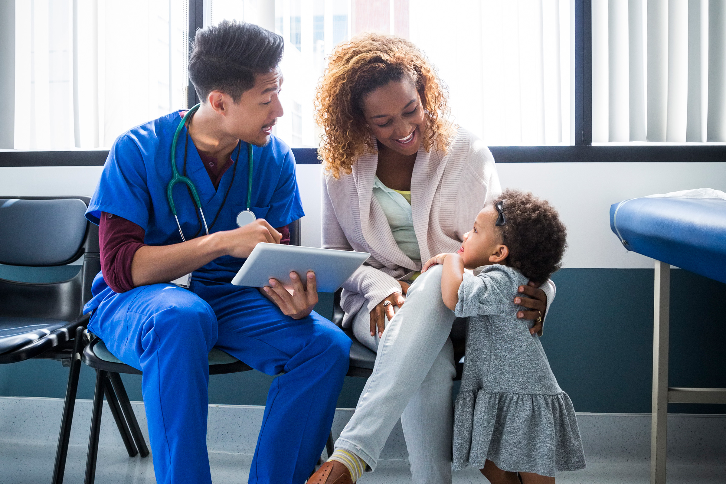 Male nurse showing digital tablet to mother by toddler in hospital